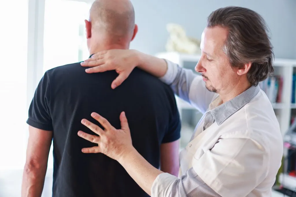 Fabrice Lefèvre évaluant le haut du dos d’un patient