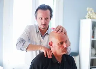 Fabrice Lefèvre examinant le cou d’un patient assis