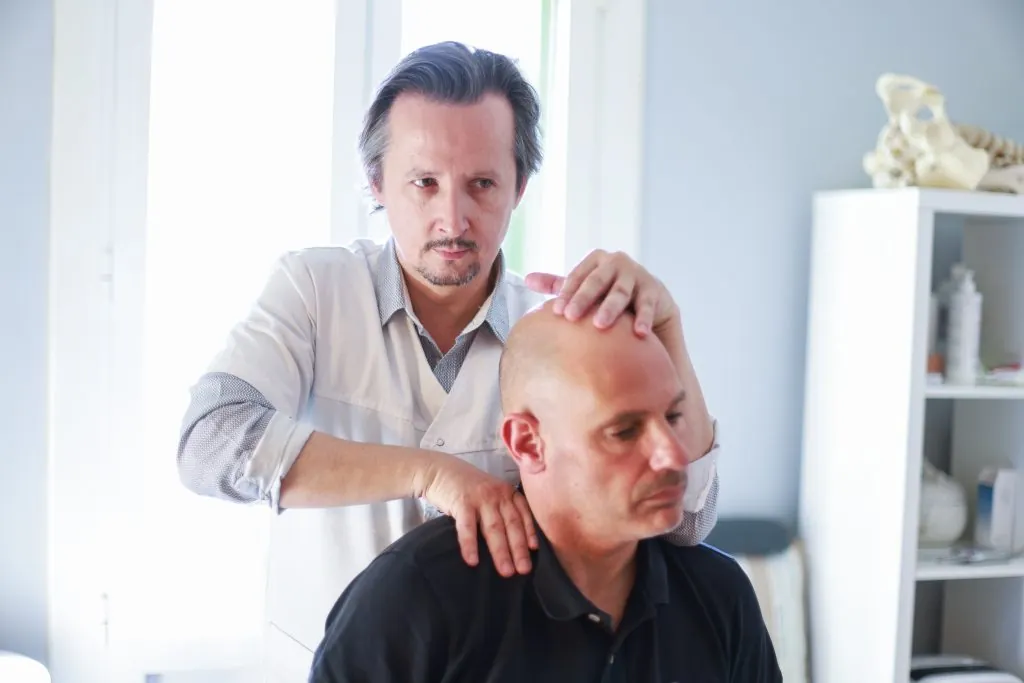 Fabrice Lefèvre examinant le cou d’un patient assis